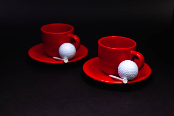 istock White golf balls and red cups of tea on the black table. 1141713444