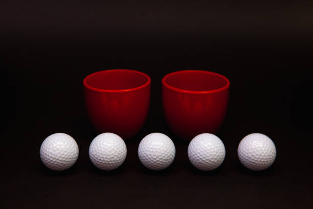 istock White golf balls and red cups of tea on the black table. 1141714174