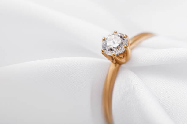 istock Beautiful gold engagement ring with a diamond on a silk fabric with copy space, close-up 1141716174