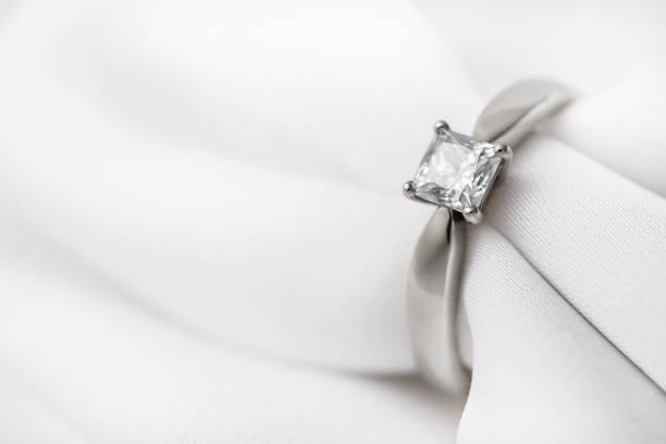istock White gold wedding ring with a large diamond on a silk fabric with copy space, close-up 1141716316