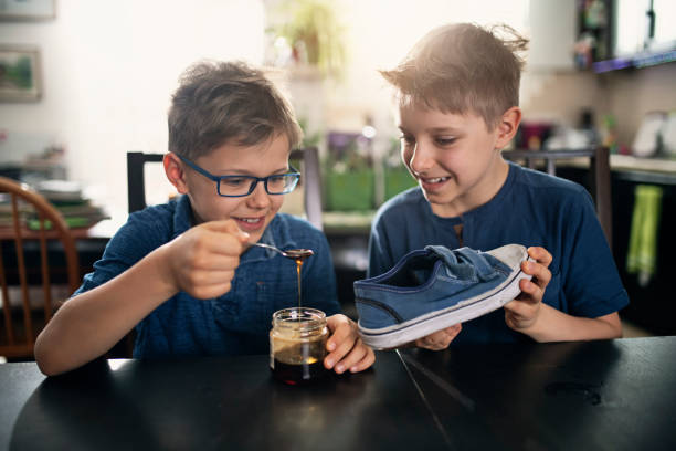 Little boys playing an April fools day prank Little boys playing an April fools day prank. The boys are pouring honey to a shoe. 
Nikon D850 april fools day stock pictures, royalty-free photos & images