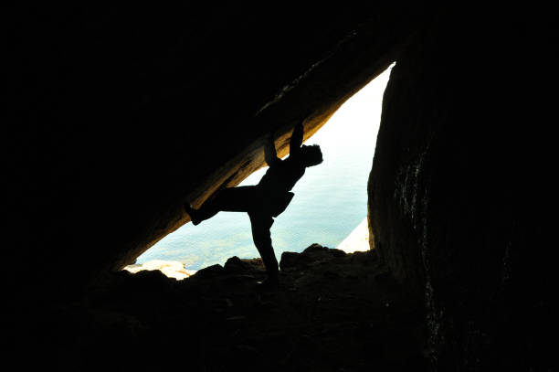 istock Man figure in cave, reverse light, climbing man, small cave entrance 1141718885