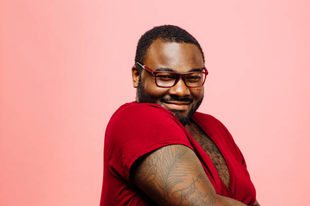 Portrait of a plus size man in red shirt and glasses smiling at the camera Portrait of a plus size man in red shirt and glasses smiling at the camera, isolated on pink background chest tattoo men stock pictures, royalty-free photos & images