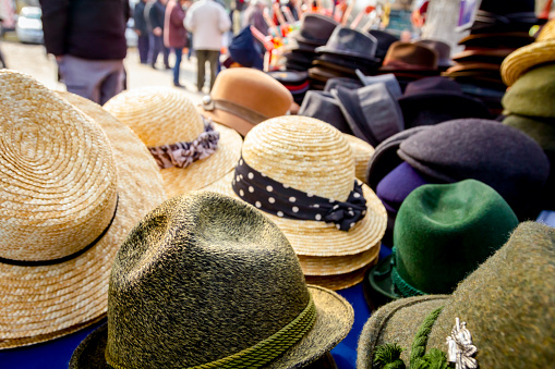 Stacked straw and cloth hats are for sale, available at flea market.