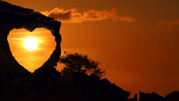 istock Heart-shaped stone on a mountain with red sky sunset background 1141727389
