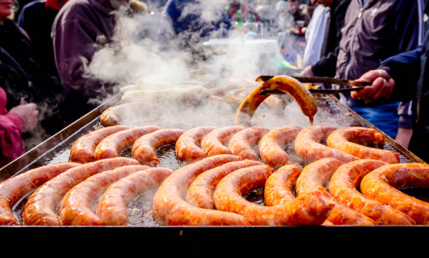 istock Turning delicious juicy sausages on the big barbecue plate with handle 1141729310