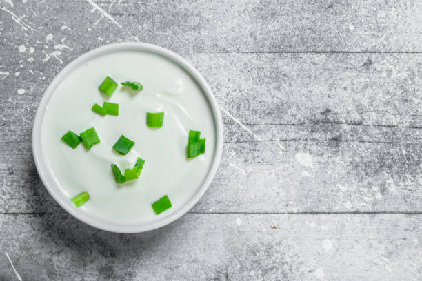 Sour cream in bowl with green onions.