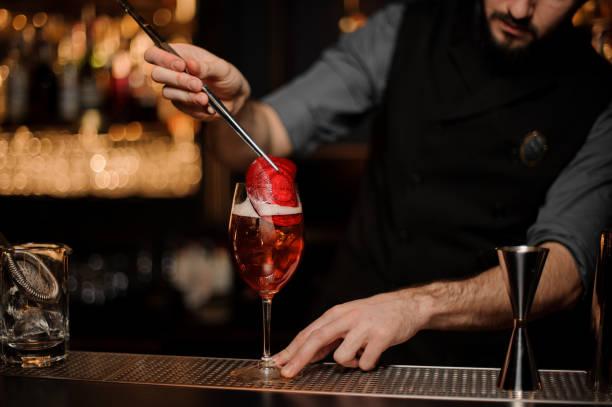 istock Professional bartender adding to a delicious cocktail red slice decor 1141737291