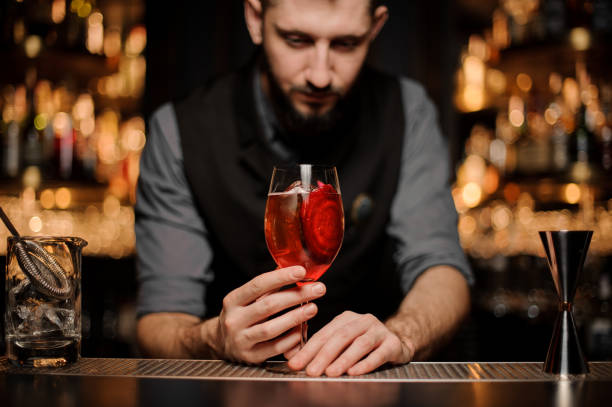 istock Red cocktail in glass in bartender's hands 1141737909