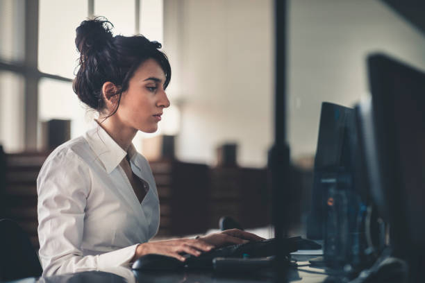 istock Beautiful young woman telephone operator with headset working on desktop computer  in  customer service call support helpline business center with teamworker in background 1141740976