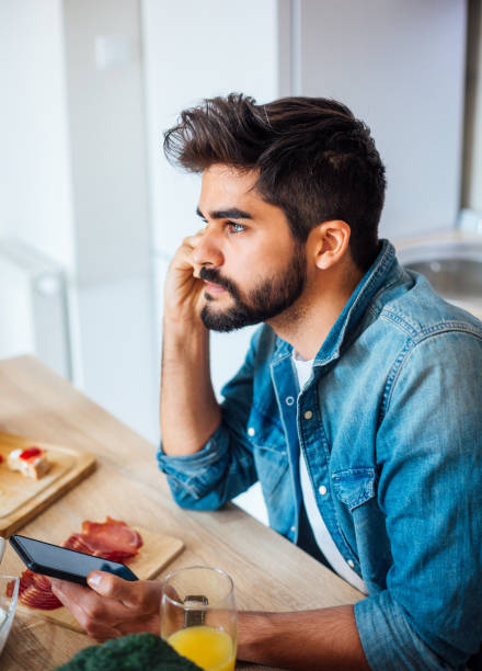 istock Happy man text messaging on cell phone during breakfast time 1141741619