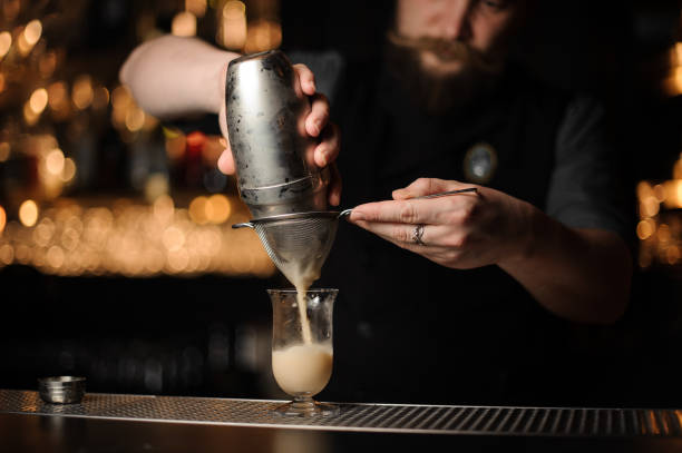 istock Professional bartender pouring cocktail from the shaker through the sieve 1141744280