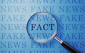 Fake News And Fact Concept - Magnifier And Fake News Text On Blue Background