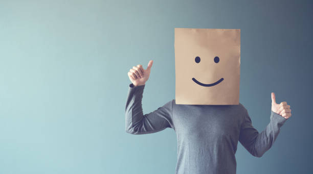 istock Man covering her face with a smiling face emoticon, copy space. 1141748402