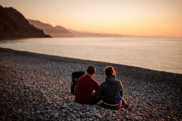 istock Young romantic happy couple sitting on the beach 1141751282