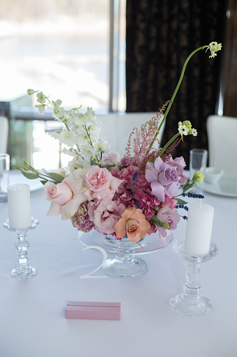 Event white restaurant table served and decorated with delicate fresh flowers.
