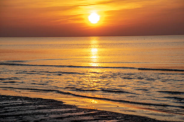 istock orabge colored sunset over calm sea beach water fields 1141755634