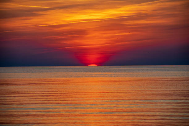 istock orabge colored sunset over calm sea beach water fields 1141756206