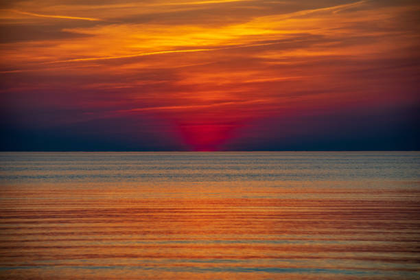 istock orabge colored sunset over calm sea beach water fields 1141756211
