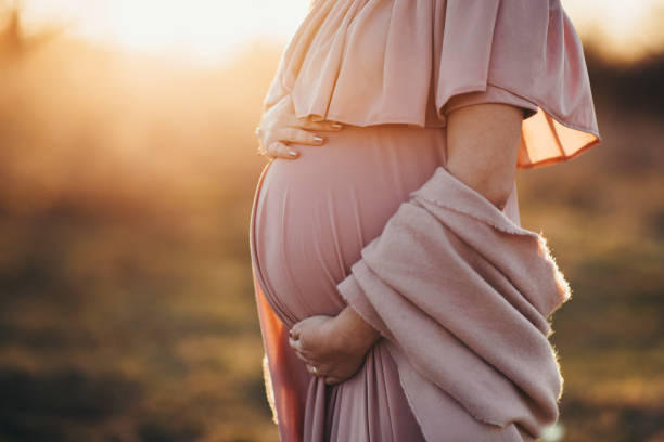 mujer embarazada con un vestido rosado polvoriento - abdomen fotos fotografías e imágenes de stock