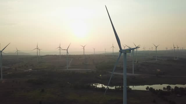 Turbin angin saat matahari terbenam menghasilkan energi terbarukan
