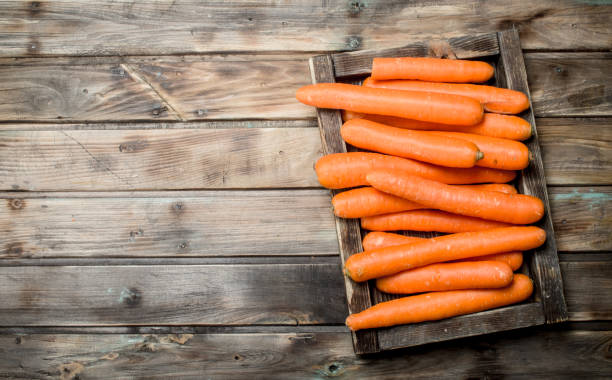 carote fresche su un vassoio di legno. - whole carrots foto e immagini stock