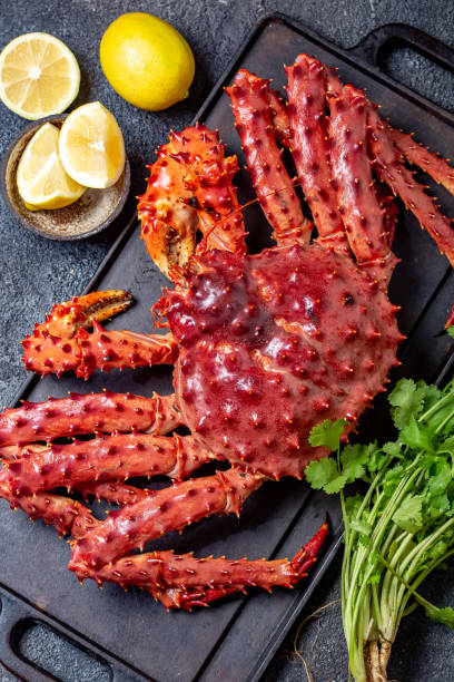 Red king crab on gray background. King crab, lemon and cilantro, top view Red king crab on gray background. King crab, lemon and cilantro, top view. crab leg photos stock pictures, royalty-free photos & images