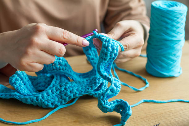 istock Extremely close knitting from beige yarn, needle, crochet hooks. Work on a new product. Selective soft focus. 1141766510
