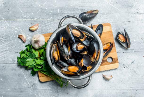 Fresh seafood clams with parsley and garlic. Fresh seafood clams with parsley and garlic. On a rustic background. mussel stock pictures, royalty-free photos & images