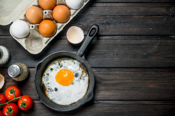istock Fried egg in a pan with a cassette of fresh eggs. 1141766811