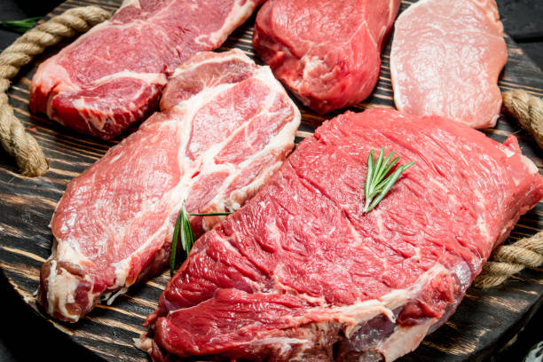 carne crua. bifes da carne e de carne de porco em uma bandeja de madeira. - steak strip steak ribeye sirloin steak - fotografias e filmes do acervo