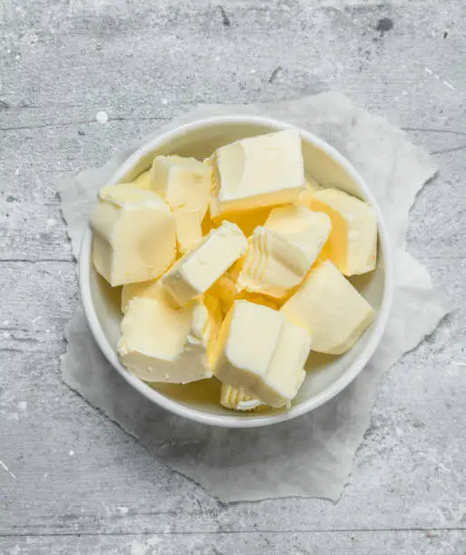 Pieces of butter in the bowl. On a rustic background.