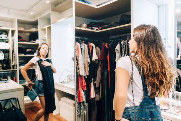 jeune adolescent essayant la robe devant le miroir - mirror women dress looking photos et images de collection