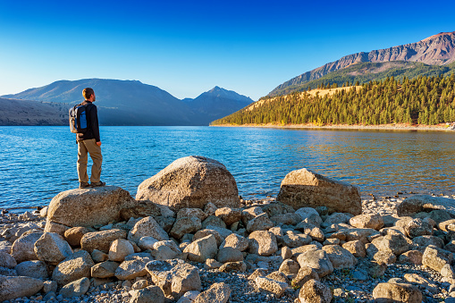 Hiker looks at view at Wallowa Lake and Wallowa Mountains near Joseph Oregon USA on a sunny morning.