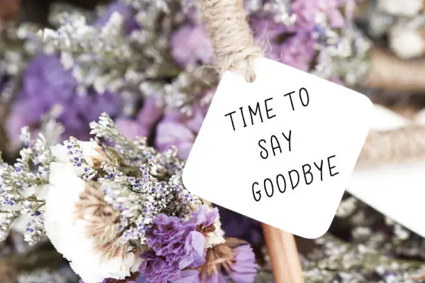 Time to say goodbye word on card and purple flower background.