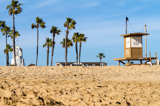 Newport Beach, CA / USA – April 6, 2019: Lifeguard Tower No. 15 on the beach with Catholic Church bell tower in the background in Newport Beach, California.
