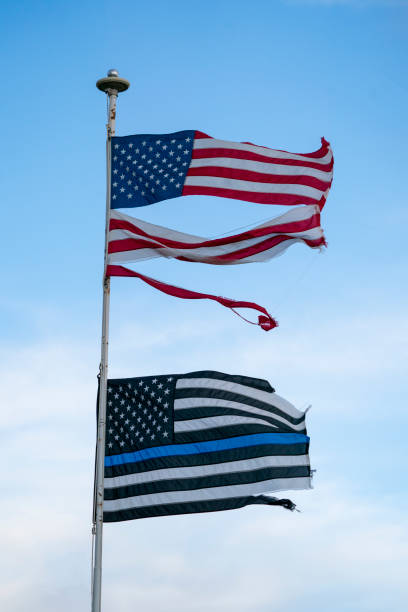 istock Torn USA Flag & a Blueline Flagin the Wind on a Flagpole 1141807944