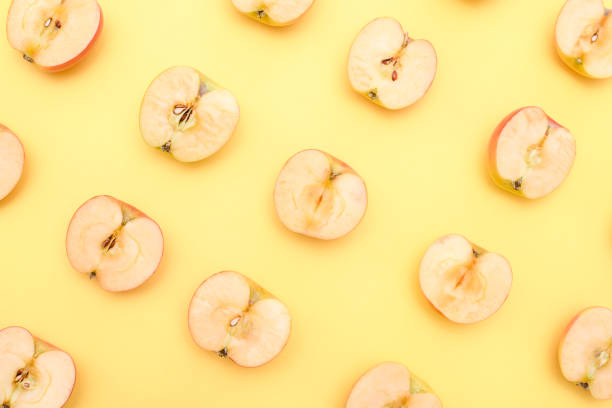 istock Background of cut in half apples on yellow background 1141812131