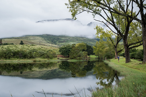 A man enjoys his time alone fly fishing in a small dam trout dam in the Drakensberg near Kwazulu-natal, South Africa