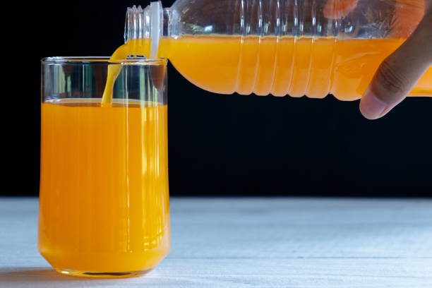 istock Pour Orange Juice , Clear Glass , Black Background , White Table 1141815554