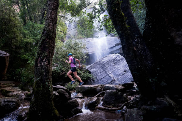 istock Woman running along a trail past the waterfall 1141817503