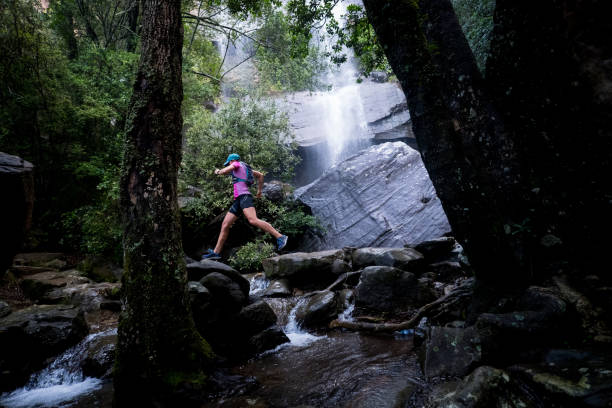 istock Woman running along a trail past the waterfall 1141817573
