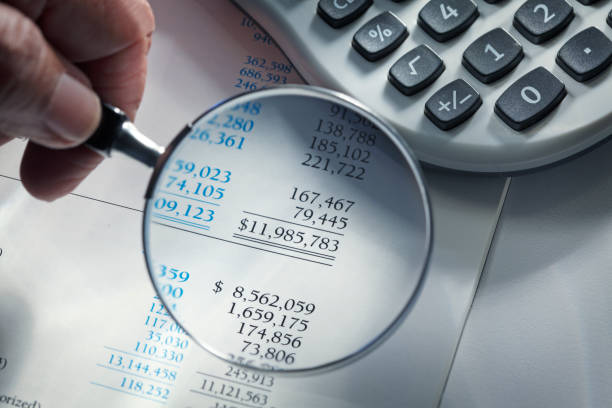 istock Man Holding Magnifying Glass Over Financial Report 1141820551