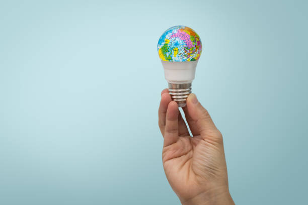 Hand is holding the LED bulb with the globe on blue
