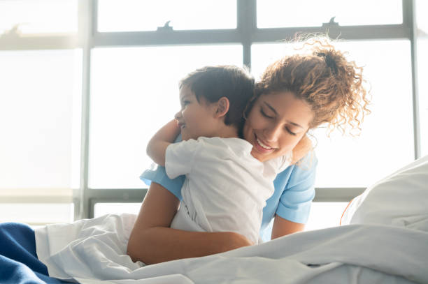 beautiful sweet little boy hospitalized in the pediatrics ward hugging young nurse - hospital patient bed nurse imagens e fotografias de stock