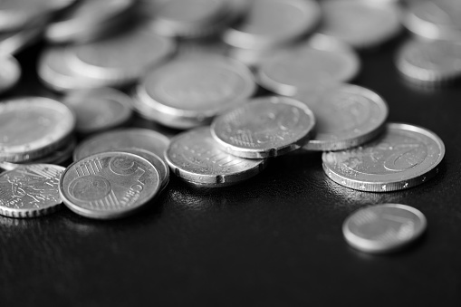 Euro coins scattered on a dark background close up. Black and white