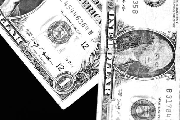 istock Two one dollar bills on a dark background close up in monochrome 1141840708