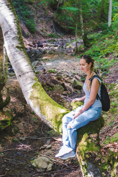 istock woman sitting no tree in forest. sun is shining on face 1141843766