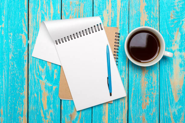 istock Cup of coffee with notebook on wooden desk 1141845660