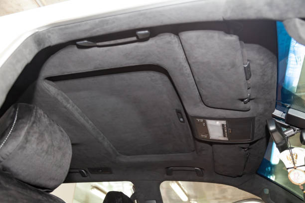istock The ceiling of the SUV car pulled by black soft material alkantara in the workshop for tuning and styling the interior, view from the passanger opened door on central mirror and sun visorson the roof 1141853073